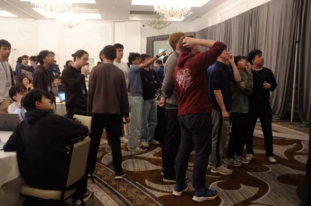 Competitors standing and watching the screens